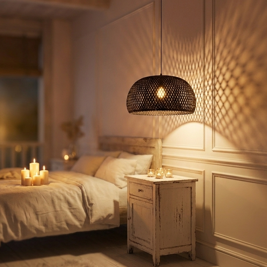 A black rattan dome pendant light hanging above a bed with lit candles, placed in a cozy bedroom setting.