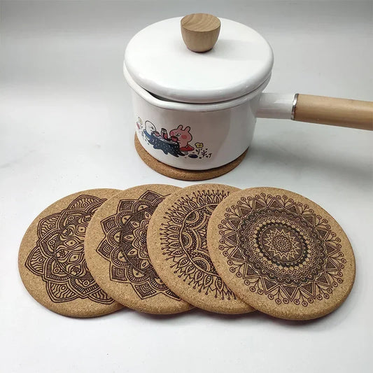 Set of six Cork coasters with intricate mandala patterns placed in front of a ceramic pot and lid on a wooden coaster, against a plain backdrop.