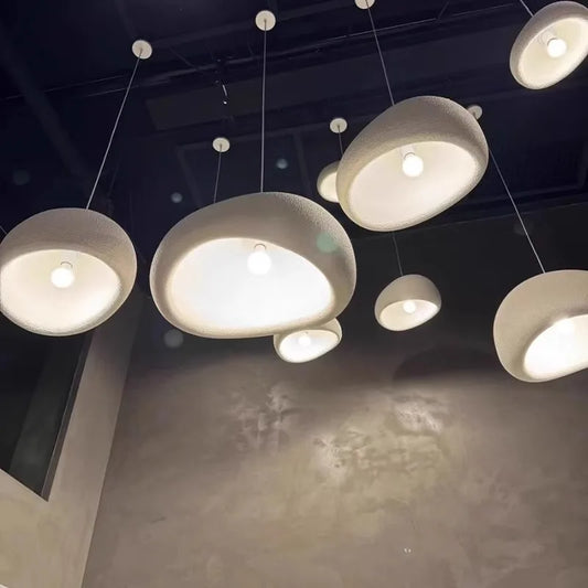 Circular, textured ceiling pendants with warm light; gray wall and black ceiling in the background.
