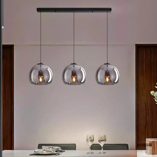 Three clear glass pendant lights hanging in a modern dining room setting