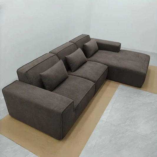 Modern corner sofa with cushions, upholstered in dark gray fabric on a wooden board with gray background