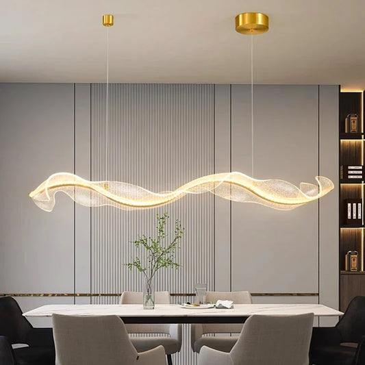 Modern wavy pendant light with transparent glass, gold ceiling fixtures, white dining room, minimalist decor.