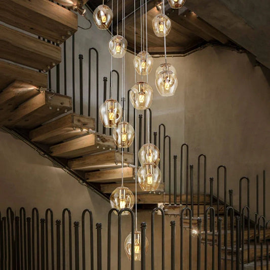 Glass dome pendant lights with metal wiring hanging above a staircase with wooden steps