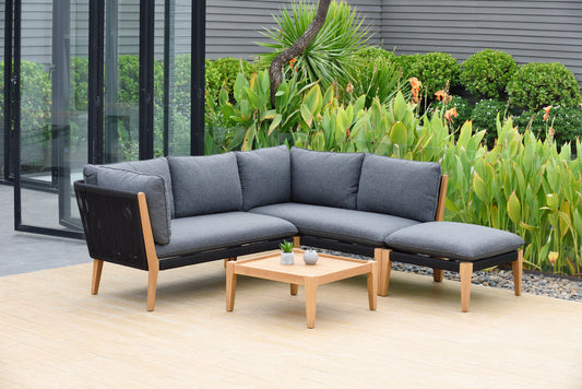 Outdoor conversation set with gray fabric seats and black frame, wooden frame legs, and a side table, in a garden setting with plants and a modern house in the background