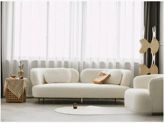 A white three-person sofa with rounded backrests and wooden legs.