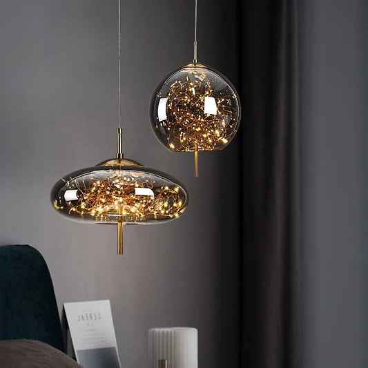 Two transparent globe pendant lamps with intricate copper wire designs hanging in a dimly lit room, showcasing modern bedroom decor.