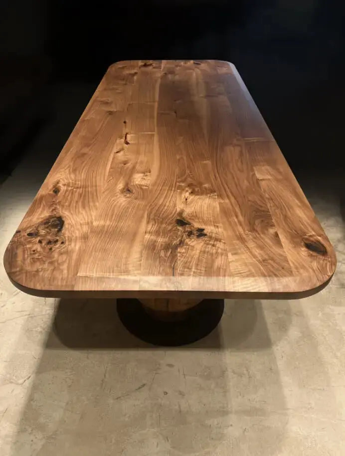 End view of the walnut dining table showing the rounded edge-glued top and tulip base