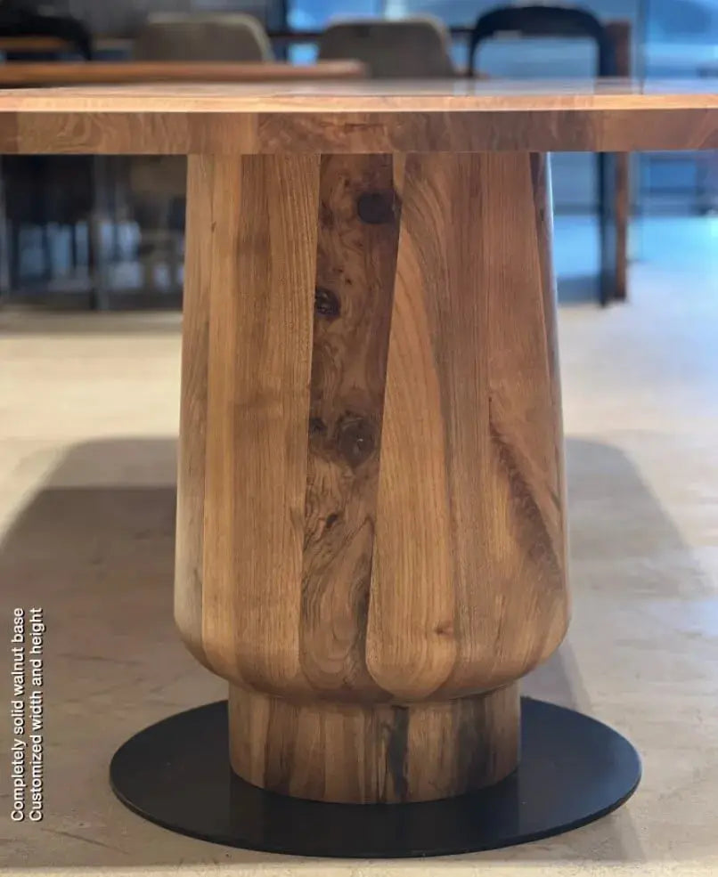 Close-up of the turned solid walnut tulip leg on its black metal disc base