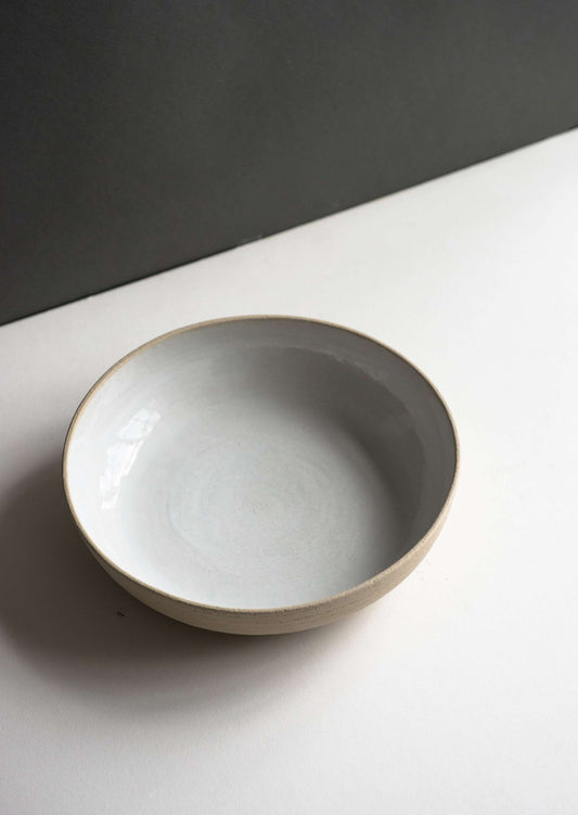 A white stoneware bowl with a glossy interior and a textured exterior against a white background.