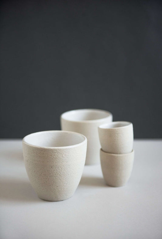 Three ceramic cups in front of a dark background