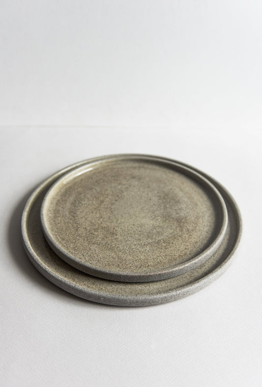 Stack of round stoneware dinner plates with a textured concrete finish in gray