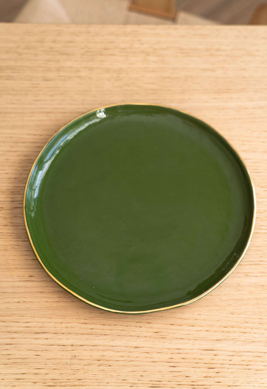 Green ceramic plate with gold rim on wooden table