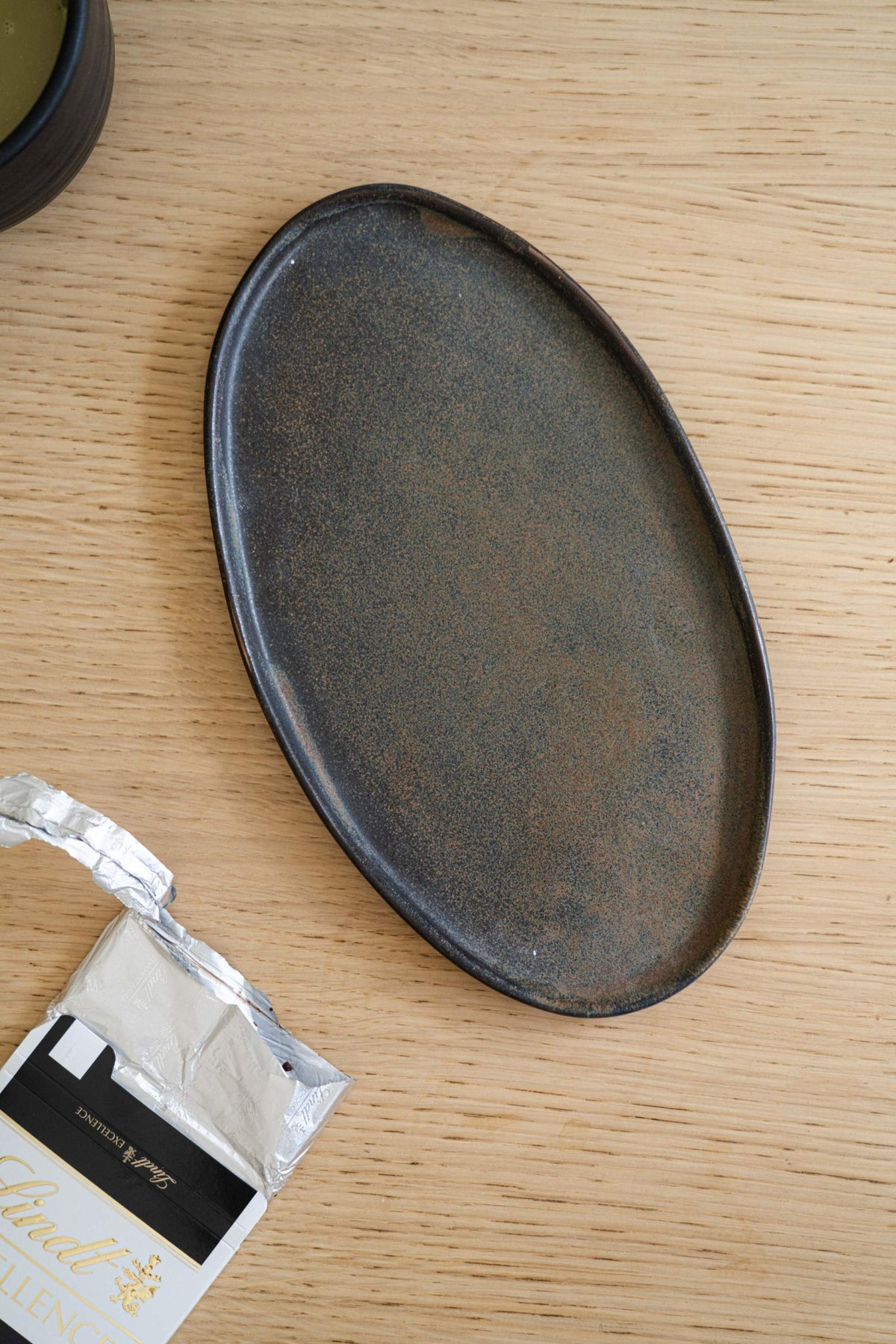 Ellipse-shaped matte serving platter with speckled texture on a wooden surface