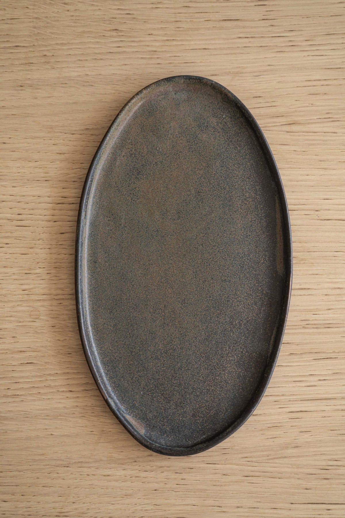 Oval matte stoneware dish on wooden surface