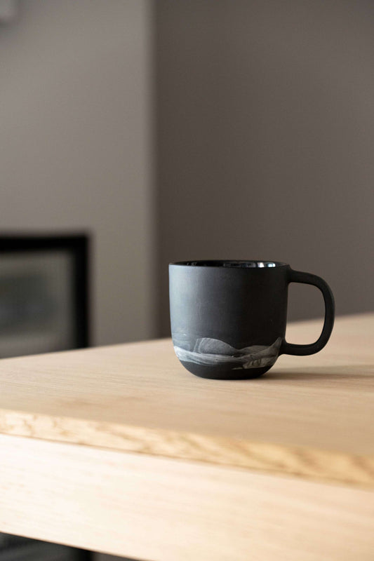 A black matte-handled mug placed on a wooden surface