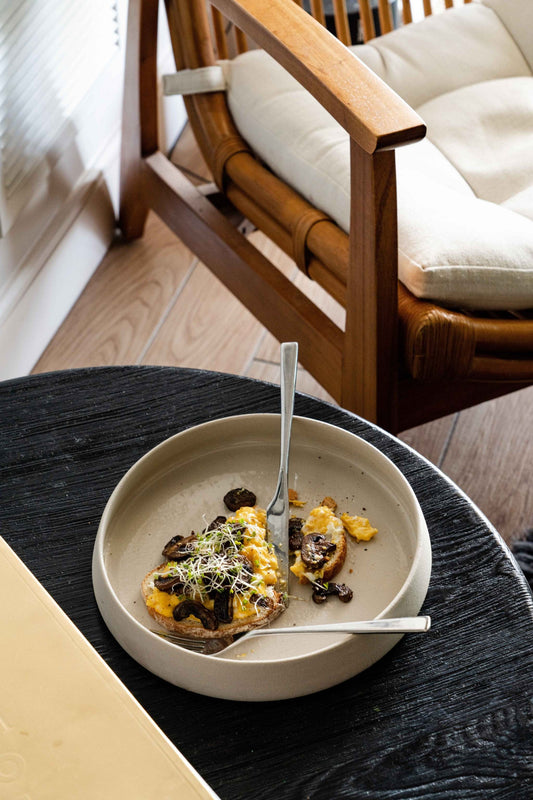 Creamy dish on modern dinner plate with fork, indoor, chair in background