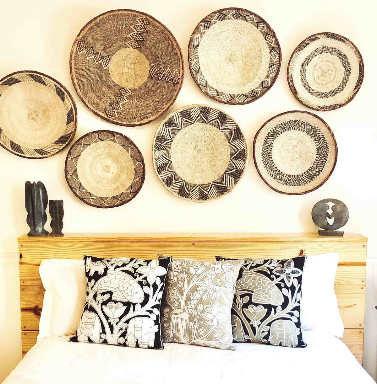 Woven baskets with intricate patterns hanging above a bed with decorative pillows.