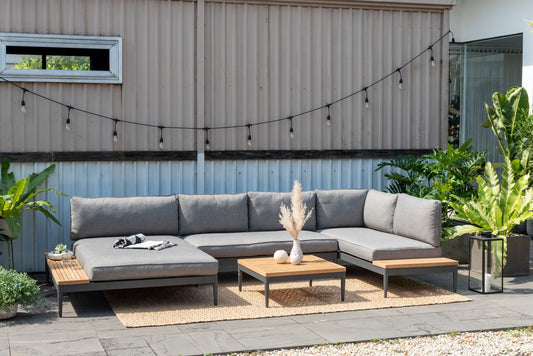 Gray modular sofa set with wooden accents and side tables on jute rug in garden setup