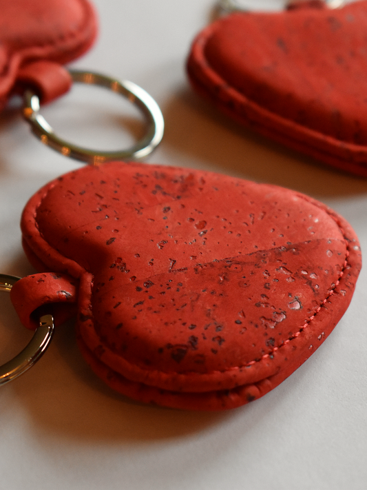 Heart-shaped keyring in textured, red material with speckles, displayed on a light background.
