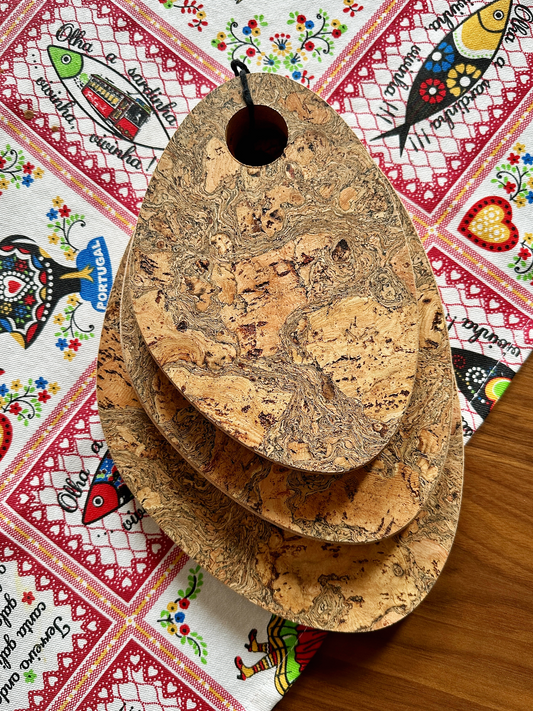 Three natural cork trivets with swirling textures under a fish-patterned fabric