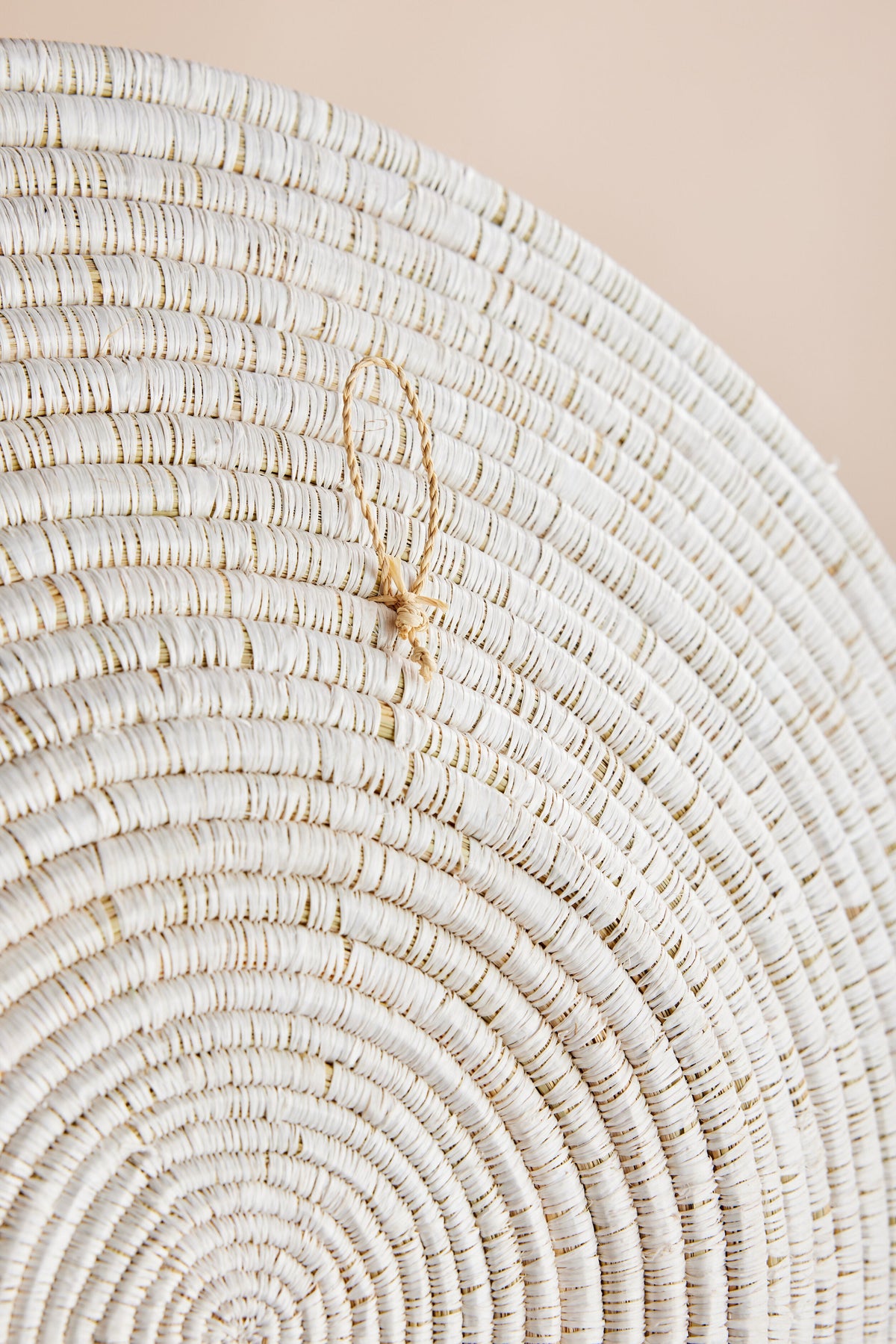 Circular white wall basket with light woven texture and small hanging loop.
