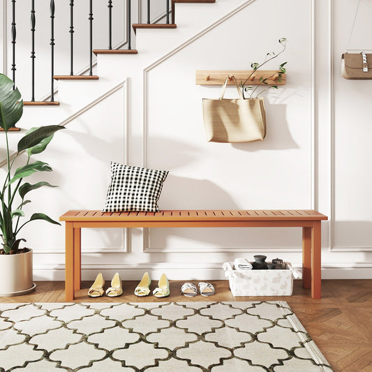 Wooden bench with a checkered pillow, teak oil finish, displayed in a minimalistic interior space with stairs, plant, and accessories.