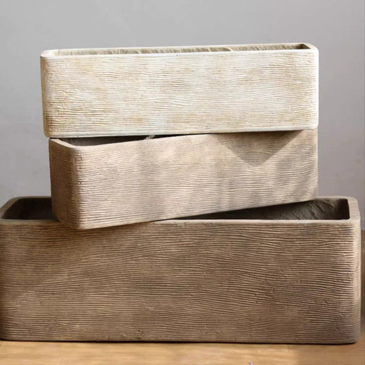 Stacked rectangular wooden planters with textured surface, light wood color, displayed on a wooden floor against a plain wall.