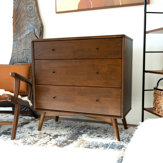 Mid-century modern solid wood dresser with three drawers, dark finish, set against a white background with artistic decor and a leather chair.