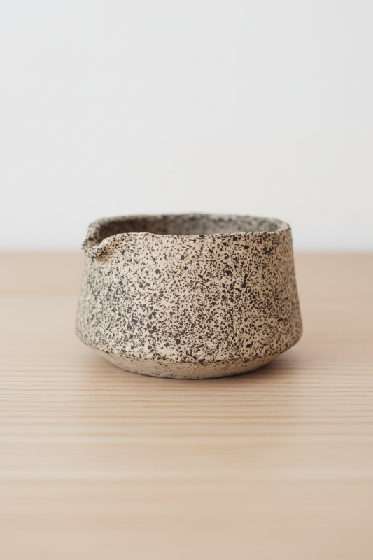 Speckled, textured stoneware bowl on wooden table