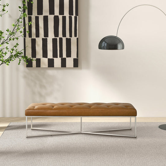 Harper premium leather bench, tan leather with white metal legs, set against a minimalist wall with a striped artwork and an arc lamp, beige rug.