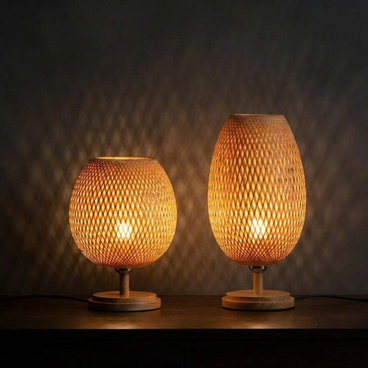 Two hand-woven bamboo table lamps with warm light illuminated on a dark surface.