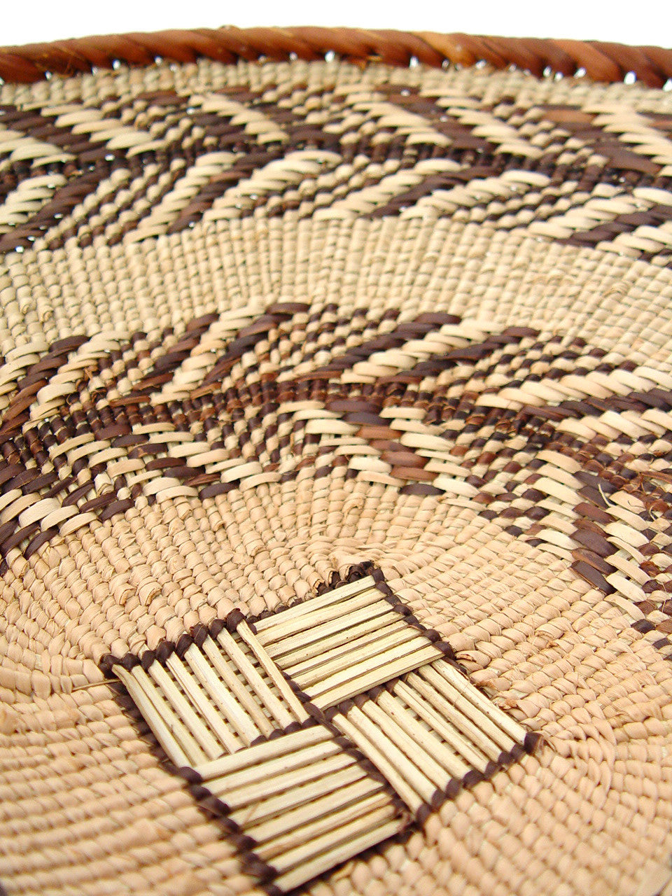 Close-up of Tonga Basket - Small, woven with natural beige and darker brown materials, showing detailed pattern.