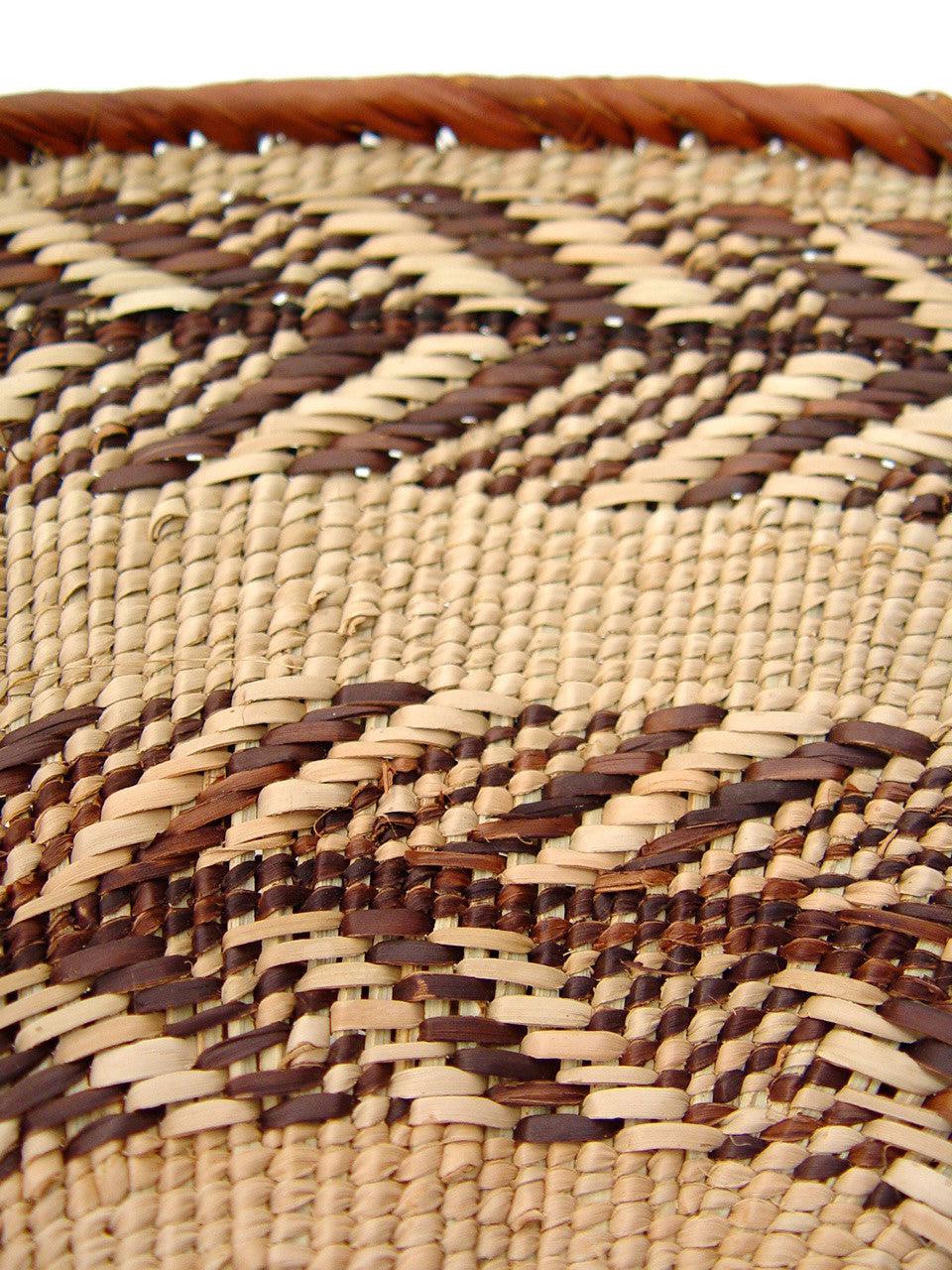 Close-up of a woven Tonga Basket with a mix of beige and brown threads, showcasing the intricate basket weaving technique.