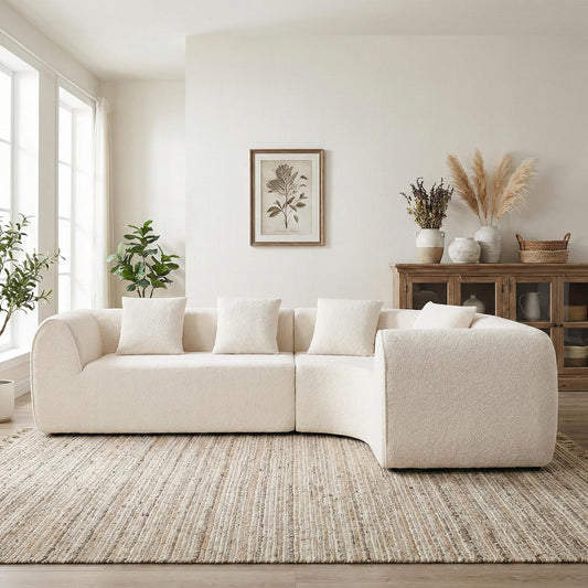 Beige boucle 2-piece sectional sofa on jute rug in light room with potted plants and cabinet with decorative items