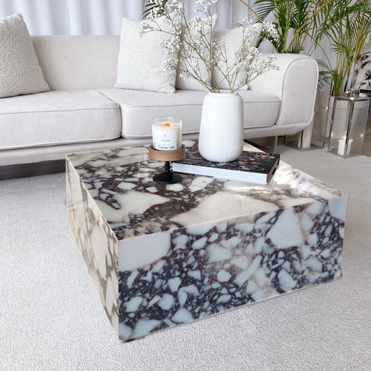 Rectangular coffee table with black and white veining, polished finish. Candle and books resting on top.
