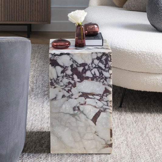 Marble side table with a white and grey pattern next to a modern couch and a cabinet in the background