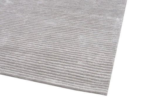 Close-up of light grey tufted bamboo wool and silk rug with vertical grooves