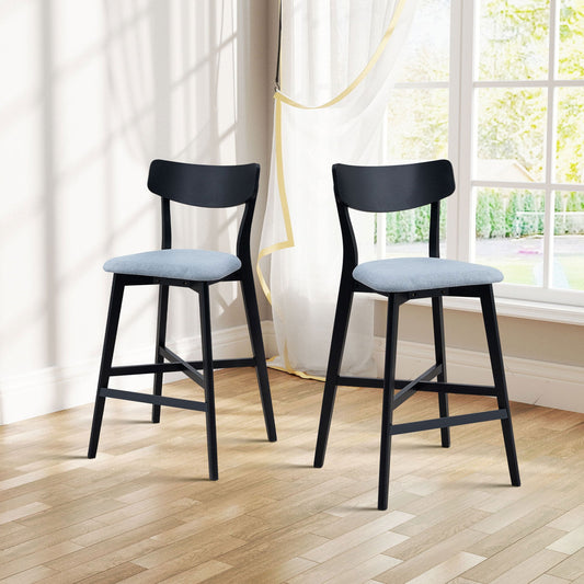 Two wooden bar chairs with light blue cushions, black legs, placed in a bright room with wooden floor and sheer curtains.
