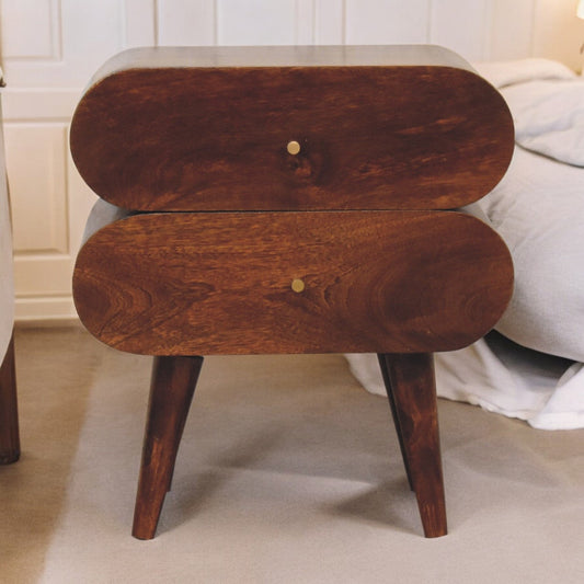 Two-tier wooden nightstand with Nordictic legs, dark wood finish, in a bedroom setting with cream bedspread.