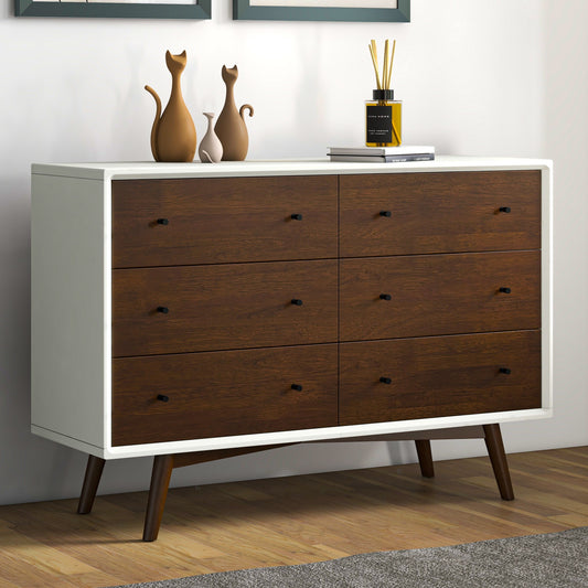Modern white dresser with dark wood drawers, black handles and legs, minimal decor on top.