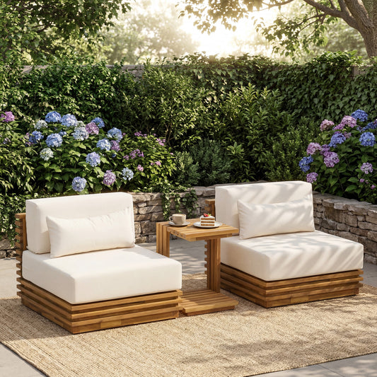 Oversized teak wood outdoor furniture set with white cushions, placed on a patio under vibrant flowers and trees