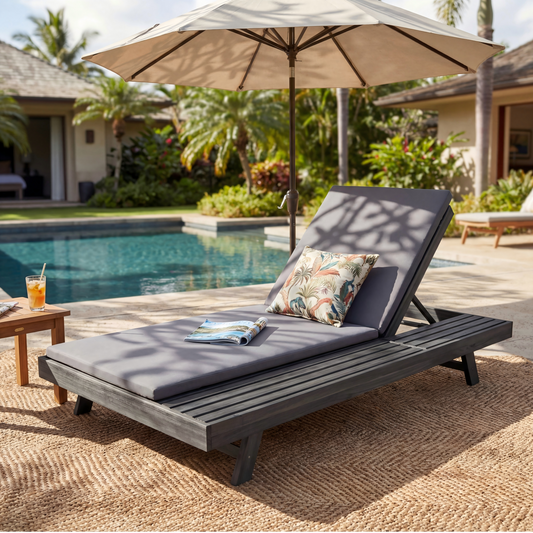 A outdoor wooden lounge chair set with gray cushions and colorful throw pillow, next to a pool with an umbrella and a drink on a side table.