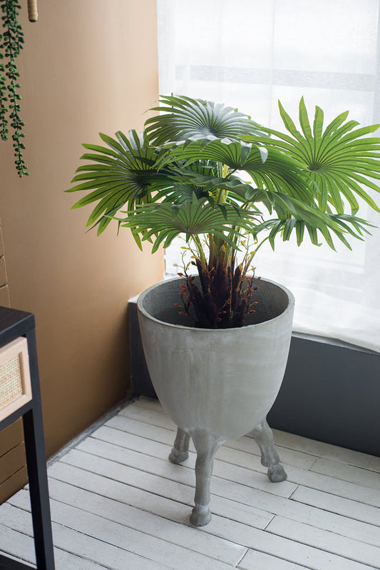 D16x22" concrete planter with legs containing a plant on a light wooden floor