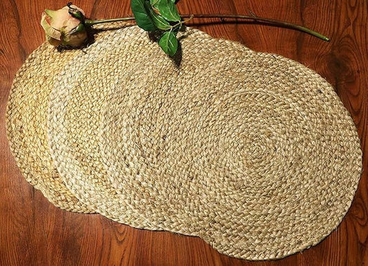 Oval jute placemat on wooden floor with dried flower