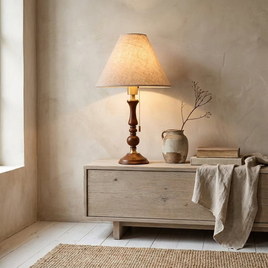 Handcrafted wooden table lamp with fabric shade on wooden side table with books and vase in neutral room.
