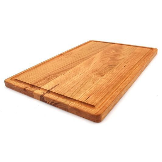Large cherry wood cutting board with juice groove on the side, polished finish, natural wood color.