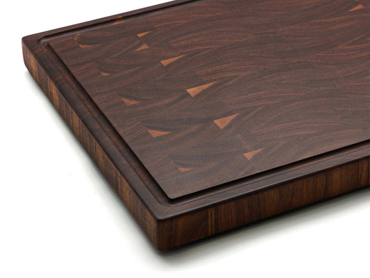 Dark walnut end-grain cutting board, showing grain and corner detail.