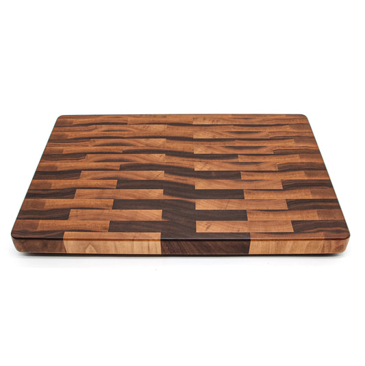 A square cutting board made of end-grain calico walnut, featuring dark grains and light wood borders, displayed against a white background.