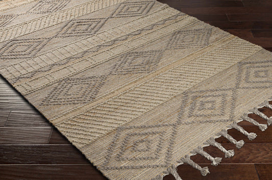 Kanata Jute&Wool Area Rug with geometric patterns and tassels, light tan color on a dark wooden floor.