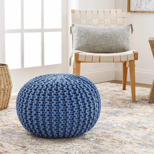 Blue knitted pouf on carpet next to woven chair
